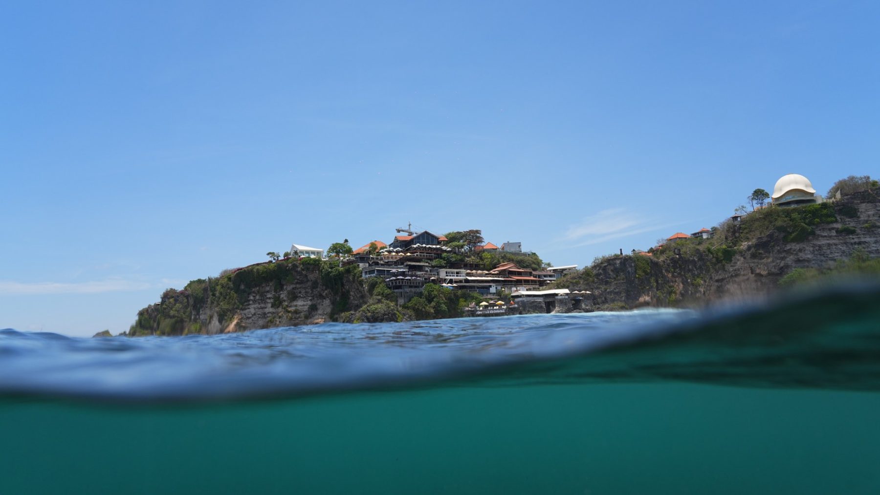 Uluwatu cliff and clifftop venues seen from the water, split level