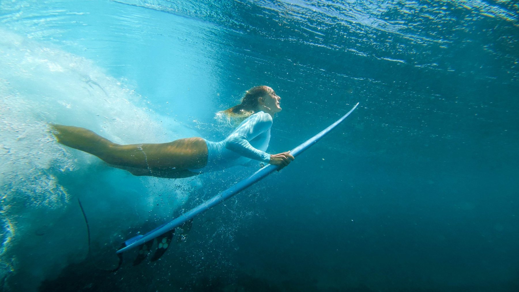 A surfer duck diving under a wave