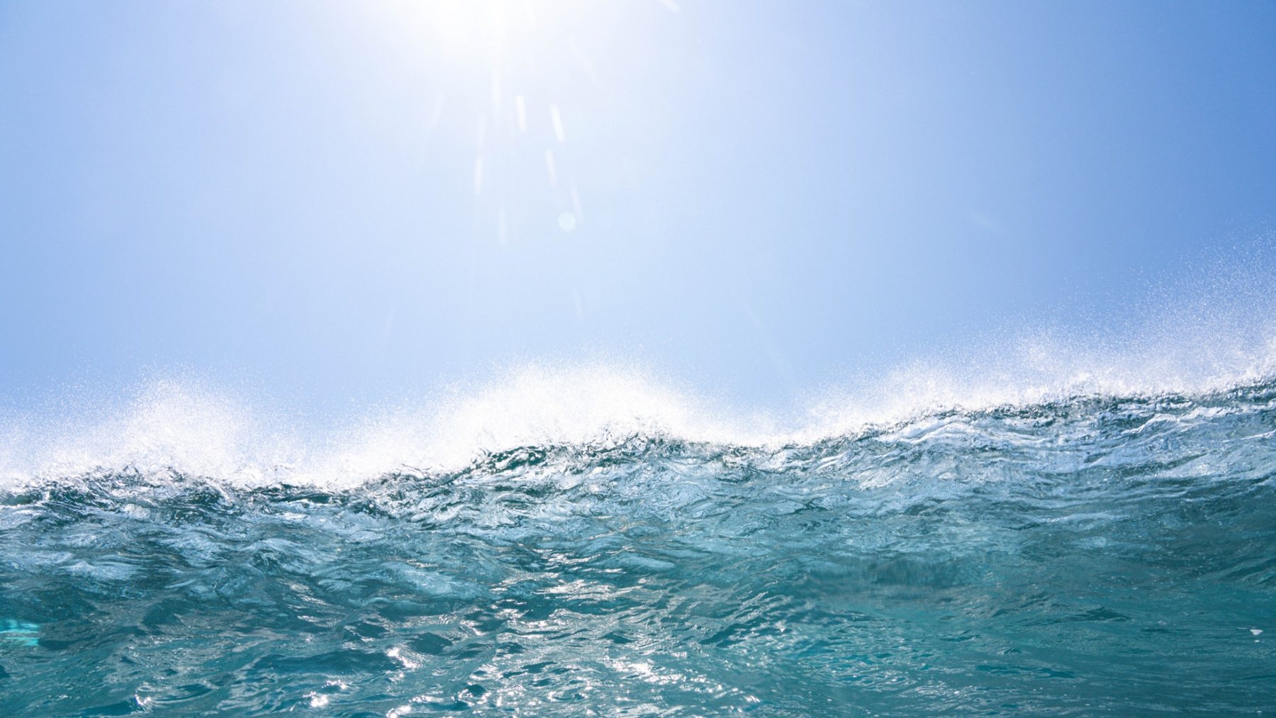 Sun over a breaking wave, shot from the water
